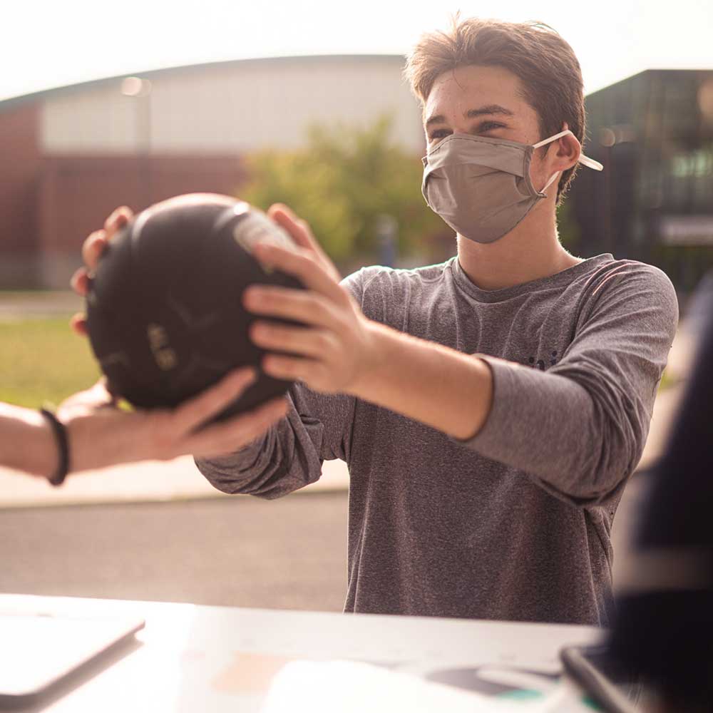 student handing volleyball to renter